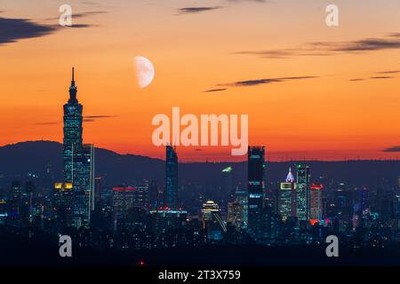 Nachts leuchten die bunten Lichter allmählich auf. Der Mond ist auch am Himmel. Orange-rote Nachtansicht auf die Stadt nach Sonnenuntergang im Herbst. Taipeh, Taiwa Stockfoto