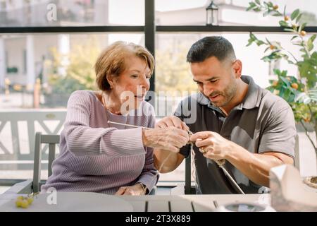 Seniorin und Krankenschwester häkeln sich im Altersheim zusammen Stockfoto