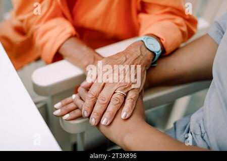 Mittelteil einer Krankenschwester- und Seniorin, die im Sitzen mit Händen tröstet Stockfoto