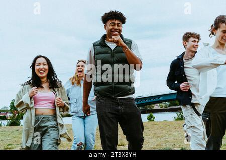 Fröhliche junge multirassische Freunde, die gegen den Himmel rennen Stockfoto