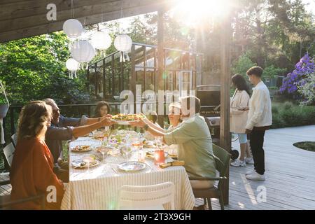 Familie und Freunde genießen im Sommer Abendessen auf der Terrasse im Hinterhof Stockfoto