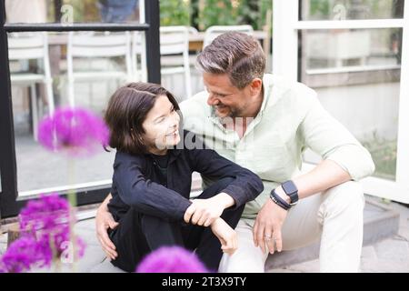 Glücklicher Vater und Sohn sehen sich an, während sie zusammen auf Stufen sitzen Stockfoto