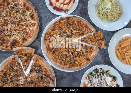 Auswahl an Pizzen und Nudelgerichten auf dem Restauranttisch Stockfoto