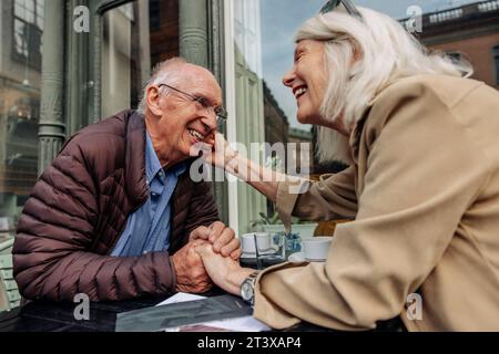 Liebevolle Seniorin, die mit einem Mann im Straßencafé sitzt Stockfoto