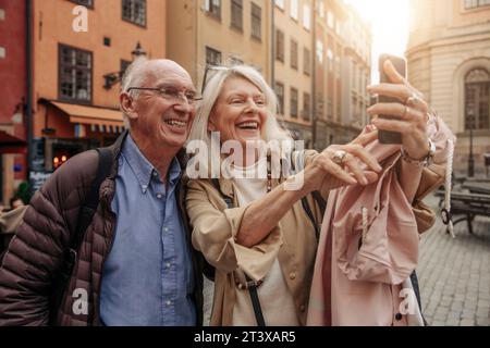 Glückliche Seniorin, die Selfie mit einem Mann in der Stadt macht Stockfoto