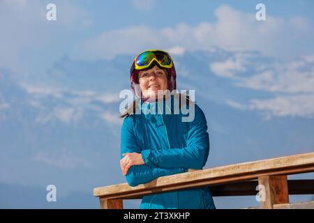 Glückliche Frau, die auf einem Holzbalkon über den Bergen steht Stockfoto