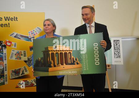 Berlin, Deutschland. Oktober 2023. Die deutsche Post gibt die erste Kryptomarke heraus, eine Kombination aus einer echten Briefmarke und einem digitalen Abdruck. Das Motiv ist das Brandenburger Tor, dargestellt durch künstliche Intelligenz. Nikola Hagleitner von der Postleitung und Bundesfinanzminister Christian Lindner halten die digitale Version der Briefmarke in Berlin, Deutschland, 26. Oktober 2023. Quelle: Zapotocky Ales/CTK Photo/Alamy Live News Stockfoto