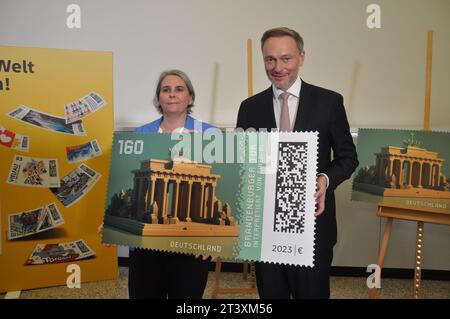 Berlin, Deutschland. Oktober 2023. Die deutsche Post gibt die erste Kryptomarke heraus, eine Kombination aus einer echten Briefmarke und einem digitalen Abdruck. Das Motiv ist das Brandenburger Tor, dargestellt durch künstliche Intelligenz. Nikola Hagleitner (links) von der Postleitung und Bundesfinanzminister Christian Lindner halten die digitale Version der Briefmarke in Berlin, Deutschland, 26. Oktober 2023. Quelle: Zapotocky Ales/CTK Photo/Alamy Live News Stockfoto