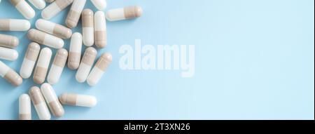 Nach dem Konzept des Medizindesigns wurde der Blick von oben auf Kapselpillen über dem blauen Tischhintergrund verschüttet. Stockfoto