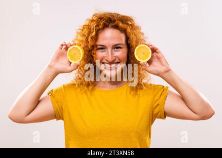 Die schöne Ingwerfrau hält Zitronenscheiben in der Hand. Stockfoto