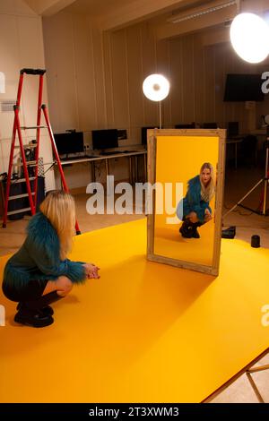 Machen Sie Fotos im Studio mit gelber Wand und einer Schönheitsscheibe mit Lichtauflage Stockfoto