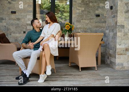 Glückliches Paar sitzt in einem Korbstuhl Stockfoto