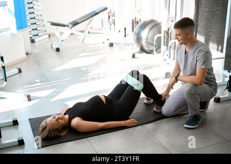 Die Frau im Fitnessstudio führt Übungen mit einem elastischen Band aus, um Fitness zu fördern Stockfoto