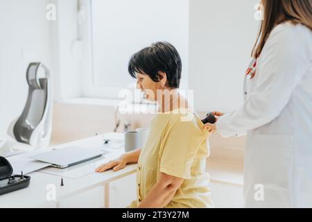 Der Arzt untersucht sorgfältig die Gesundheit der älteren Frau, misst den Blutdruck, kontrolliert die Atmung und bietet professionelle medizinische Versorgung. Stockfoto