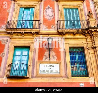 Flacher Blick auf die Fenster und die alte Fassadenwand. Es gibt ein Schild mit der Aufschrift Plaza del Cardenal Belluga. Stockfoto