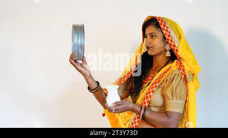 Eine junge Rajasthani-Frau indischer Herkunft, die beim Karwa Chauth Festival durch das Sieb schaut. Stockfoto