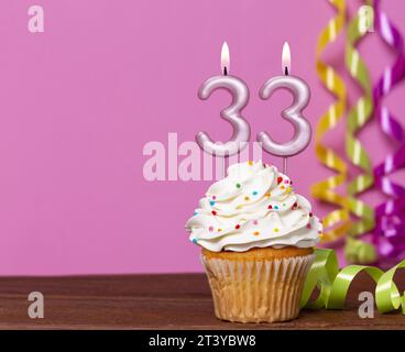 Geburtstagskuchen Mit Kerzennummer 33 - Auf Rosafarbenem Hintergrund. Stockfoto