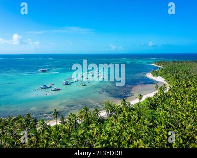 Blick aus der Vogelperspektive auf die Yachten, die in einer wunderschönen Lagune mit türkisfarbenem Meerwasser an einem wilden tropischen Strand mit Palmen und weißem Sand vertäut sind Stockfoto