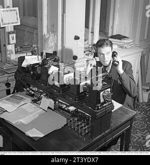 In den 1940er Jahren Ein Mann in einem Büro, der beschäftigt aussieht und gleichzeitig in zwei Telefonen spricht. Schweden 1947. Kristoffersson Ref. AA37-11 Stockfoto