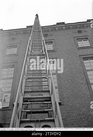 Feuer in den 1940ern Der Feuerwehrmann von Kungsholmen's Feuerwache geht die Leiter hoch, die gegen ein Haus aufgestellt ist. Schweden Februar. 1940. Kristoffersson Ref. 56-11 Stockfoto