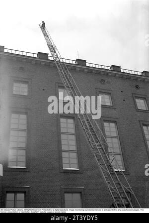 Feuer in den 1940ern Der Feuerwehrmann von Kungsholmen's Feuerwache geht die Leiter hoch, die gegen ein Haus aufgestellt ist. Schweden Februar. 1940. Kristoffersson Ref. 56-10 Stockfoto