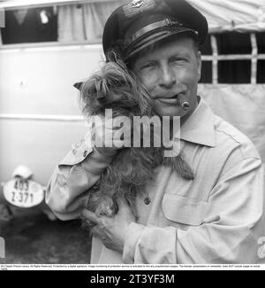 In den 1950er Jahren Ein Mann, der zusammen mit seinem kleinen Hund dargestellt wird, den er sichtbar mag und hält. Er raucht eine Zigarre und trägt eine Mütze. Schweden 1951. Kristoffersson Ref. BP31-2 Stockfoto