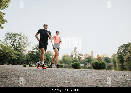 Aktive Freunde, die im Freien trainieren: Fitte Paare, die mit Sportlehrern im Park laufen Stockfoto