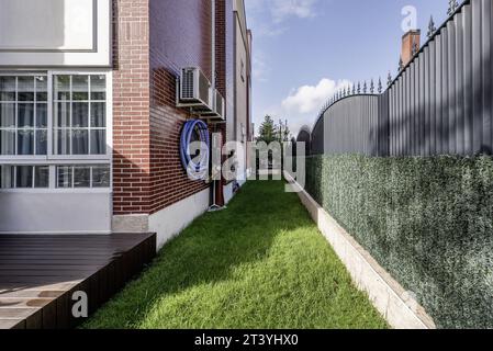 Kleines, langgestrecktes Grasfeld, das den Umkreis eines Einfamilienhauses umgibt Stockfoto