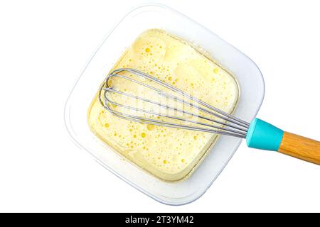 Teig in Schüssel und Schneebesen auf weißem Hintergrund Stockfoto