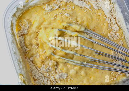 Teig in der Schüssel und Schneebesen auf weißem Hintergrund von oben Stockfoto