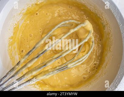 Cupcake-Teig und Schneebesen auf weißem Hintergrund, Draufsicht Stockfoto