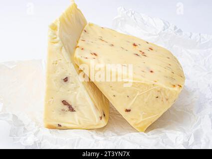 Stück Käse mit Nüssen und Paprika auf weißem Minzpapier Stockfoto
