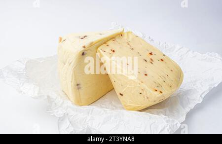 Stück Käse mit Nüssen und Paprika auf weißem Minzpapier Stockfoto
