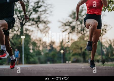 Aktives Paar motiviert sich gegenseitig beim Laufen im Park. Stockfoto