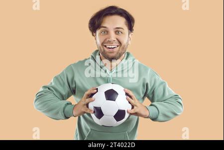 Porträt eines glücklichen, begeisterten Fußballspielers oder Sporttrainers, der Fußball hält und lächelt Stockfoto