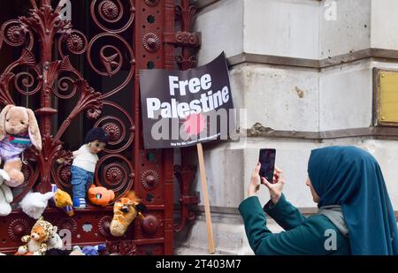 London, Großbritannien. Oktober 2023. Eine Frau fotografiert die Spielzeuge am Eingang des Außenministeriums während der Demonstration. Eltern und Kinder versammelten sich vor dem Außenministerium, dem Commonwealth- und Entwicklungsbüro in Westminster, um einen sofortigen Waffenstillstand in Gaza zu fordern und legten Teddybären und anderes Spielzeug, das die während des israelisch-Hamas-Krieges getöteten palästinensischen Kinder repräsentierte, vor dem Regierungsgebäude. Quelle: SOPA Images Limited/Alamy Live News Stockfoto