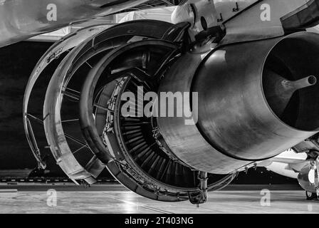 Flugzeugdetails. Wartung des Flugzeugtriebwerks im Hangar bei Nacht. Schwarzweißfoto. Stockfoto