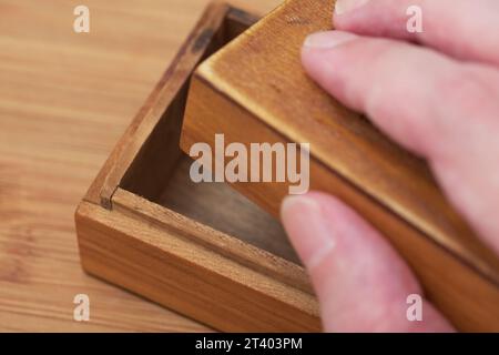 Ein Mann, der mit der Hand eine kleine leere Holzkiste öffnet. Nahaufnahme. Stockfoto