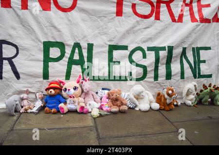 London, Großbritannien. Oktober 2023. Während der Demonstration werden neben einem Pro-Palästina-Banner Spielzeug gesehen. Eltern und Kinder versammelten sich vor dem Außenministerium, dem Commonwealth- und Entwicklungsbüro in Westminster, um einen sofortigen Waffenstillstand in Gaza zu fordern und legten Teddybären und anderes Spielzeug, das die während des israelisch-Hamas-Krieges getöteten palästinensischen Kinder repräsentierte, vor dem Regierungsgebäude. Quelle: SOPA Images Limited/Alamy Live News Stockfoto