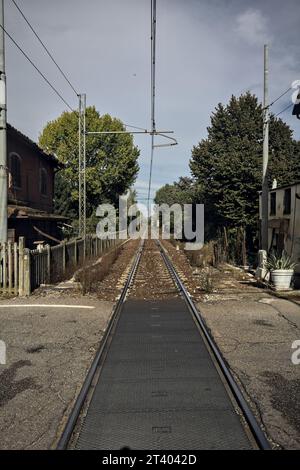 Eisenbahnüberquerung durch ein Dorf und einen Park an einem sonnigen Tag Stockfoto