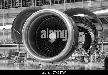 Nahaufnahme einer zerlegten Turbine eines Flugzeugs im Hangar. Demontage und Reparatur werden durchgeführt. Schwarzweißfoto. Stockfoto