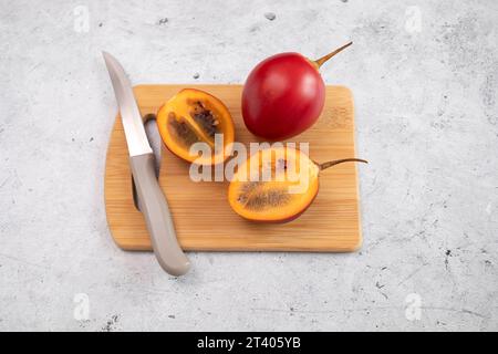 Frisch Geschnittene Exotische Frucht Tamarillo Auf Bewaldetem Schneidebrett Mit Messer. Eiförmige essbare Frucht, bekannt als Baumtomate, Pflanzenfamilie Solanaceae, Solanum Stockfoto