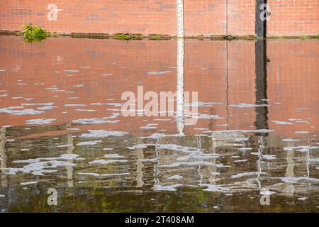 Taplow, Großbritannien. Oktober 2023. Heute gab es eine große Menge weißen Schaum auf dem Jubilee River in Taplow, Buckinghamshire. Der Jubilee River ist ein von Menschenhand geschaffenes Hochwasserschutzsystem, das von der Umweltbehörde verwaltet wird und bei starkem Regen überschüssiges Wasser aufnimmt und so dazu beiträgt, Windsor, Maidenhead und Dorney vor Überschwemmungen zu schützen. Pflanzenschutt, brauner Schlamm und Entengras haben sich hinter dem gelben Bummel am Wehr zurückgebildet, aber im eigentlichen Wehr am Jubliee River und danach gab es viel mehr weißen Schaum als sonst auf der Oberfläche des Flusses heute. Es ist möglich, dass dies der Fall ist Stockfoto