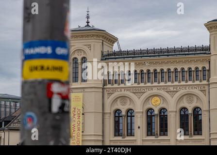 Ein Bild des Friedensnobelzentrums und ein verschwommener Aufkleber Hände weg von der Ukraine im Vordergrund. Stockfoto