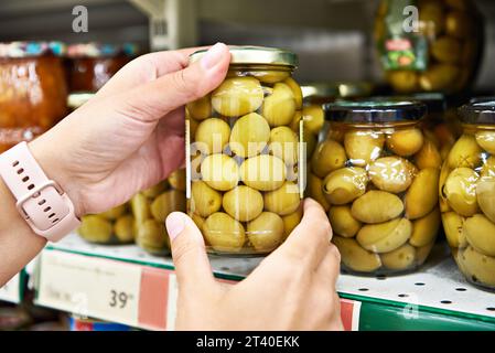 Oliven in Dosen in den Händen eines Käufers in einem Geschäft Stockfoto