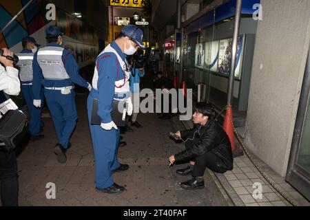 Tokio, Japan. Oktober 2023. Mitglieder der Shibuya-Sicherheitspatrouille weisen einen Mann an, seine Zigarette zu löschen, da das Rauchen für die Nacht verboten ist. hat Halloween-Feiern verboten und ausländische Touristen gewarnt, sich von Shibuya fernzuhalten, nachdem sie eine mehrjährige Kampagne durchgeführt hatten, um die Volksversammlung zu töten, indem sie vor einer potenziellen Schreckenssituation warnten, obwohl es keine Vorfälle gab, die eine Katastrophe in Tokio nach Itaewon-Art zur Kontrolle der Menschenmenge beinhalteten. Trinken und Rauchen sind in Shibuya-ku an Halloween vorübergehend verboten. (Kreditbild: © Taidgh Stockfoto