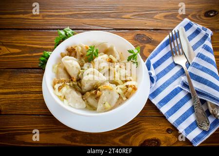 Ukrainischer Vareniky oder Pierogi gefüllt mit Kartoffeln und Pilzen, serviert mit gebratenen Zwiebeln. Holztischhintergrund. Hochwertige Fotos Stockfoto