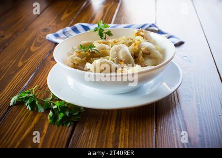 Ukrainischer Vareniky oder Pierogi gefüllt mit Kartoffeln und Pilzen, serviert mit gebratenen Zwiebeln. Holztischhintergrund. Hochwertige Fotos Stockfoto