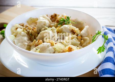 Ukrainischer Vareniky oder Pierogi gefüllt mit Kartoffeln und Pilzen, serviert mit gebratenen Zwiebeln. Holztischhintergrund. Hochwertige Fotos Stockfoto