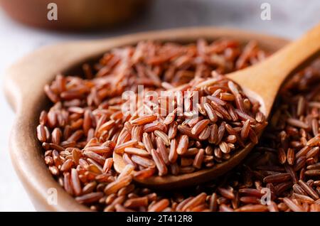 Nahaufnahme roher Reis in einer Tonschale mit einem Holzlöffel. Stockfoto